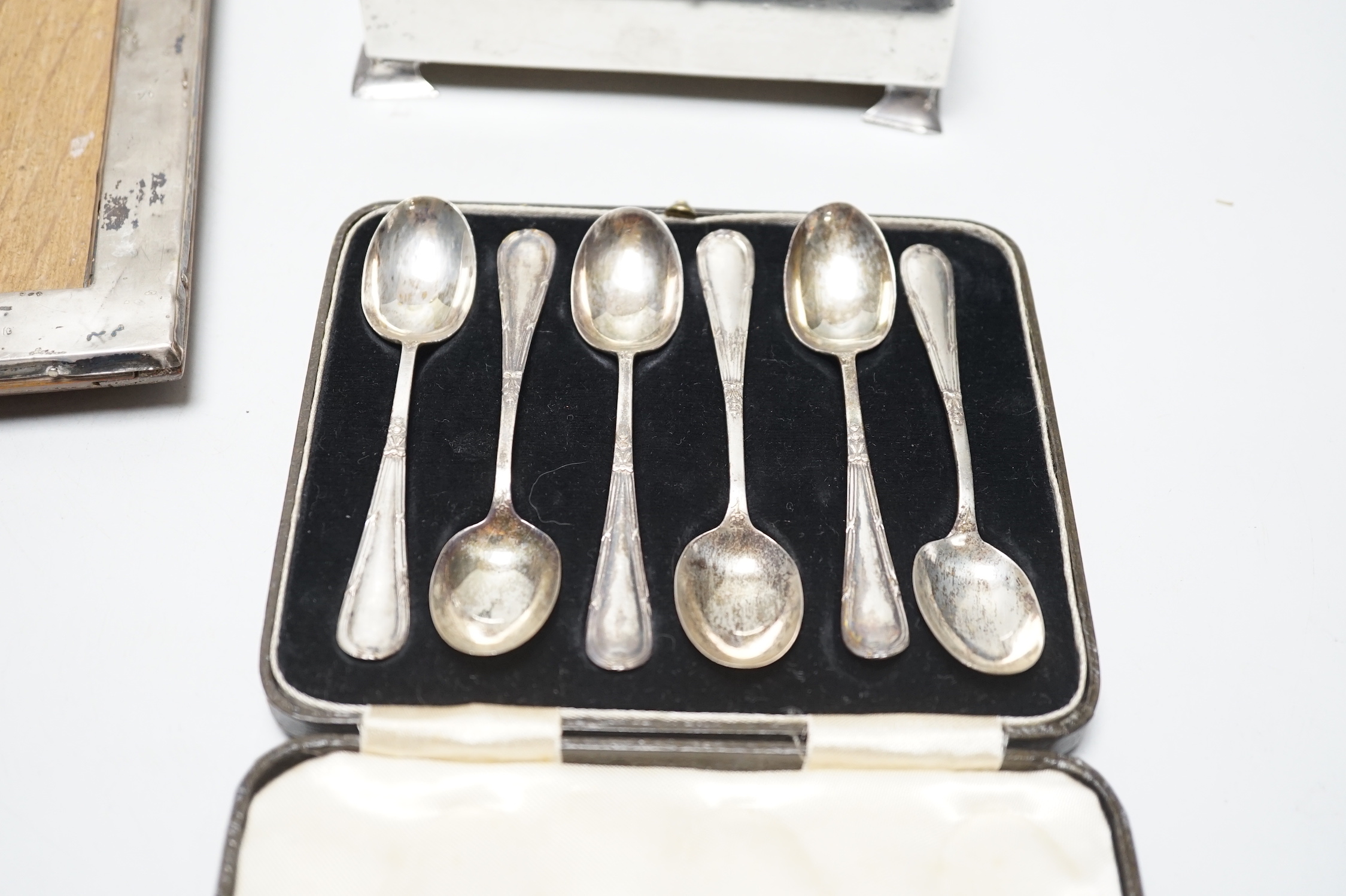 A set of six George VI silver teaspoons, Birmingham, 1939, cased, a silver cigarette box and a silver framed photograph frame.